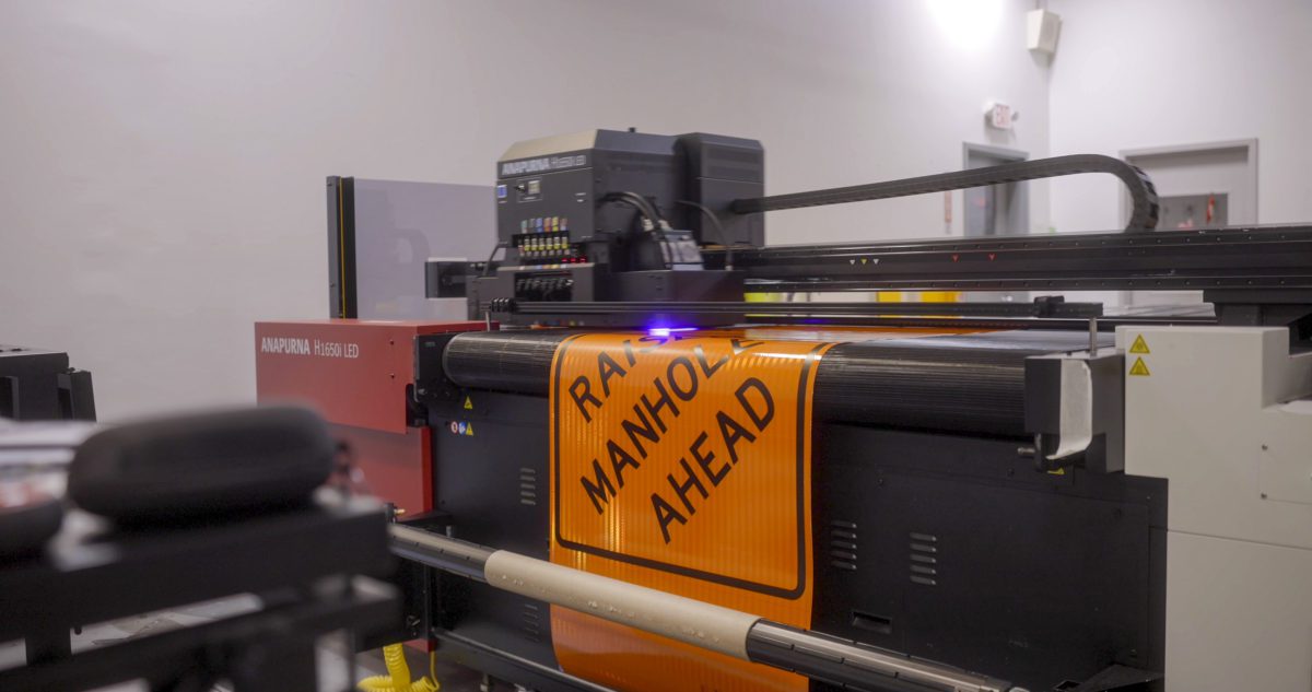 Large-format UV printer producing an orange work zone sign